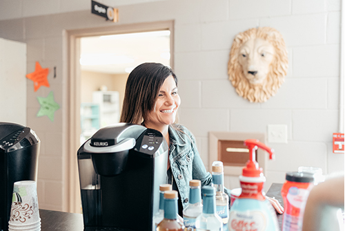 A volunteer smiling behind the coffee counter at the Rendezvous Cafe